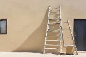 Exterior painting and waterproof wall coating service for Abu Dhabi villas, showing fresh beige paint applied with roller and bucket